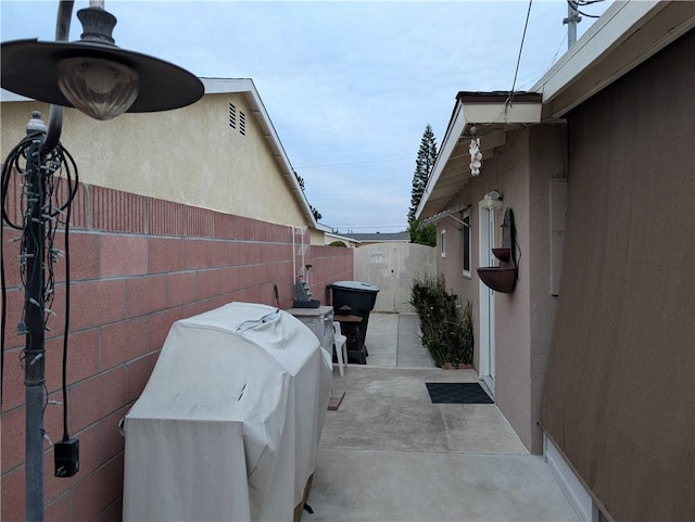 view of home's exterior with stucco siding, a patio, and fence