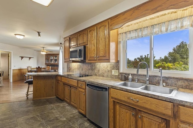 1170 Avocado Ave, Escondido, CA 92026 - kitchen featuring a sink, a peninsula, a kitchen bar, brown cabinetry, and appliances with stainless steel finishes