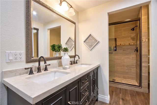 bathroom with a stall shower, double vanity, and a sink