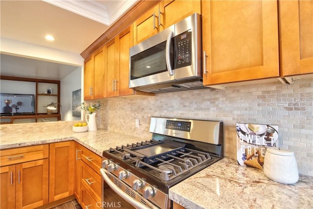 kitchen featuring light stone countertops, appliances with stainless steel finishes, brown cabinets, backsplash, and crown molding