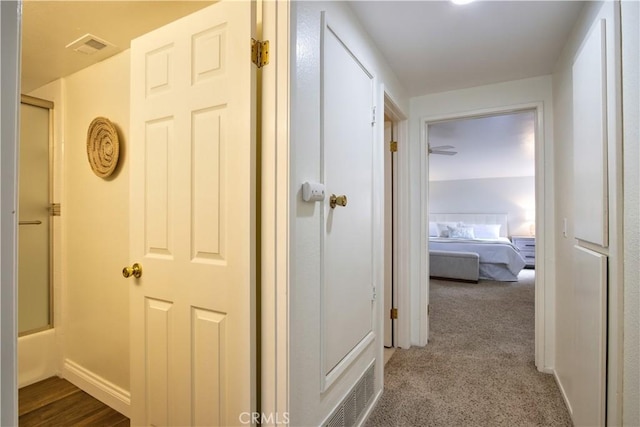 hall with visible vents, carpet floors, and baseboards