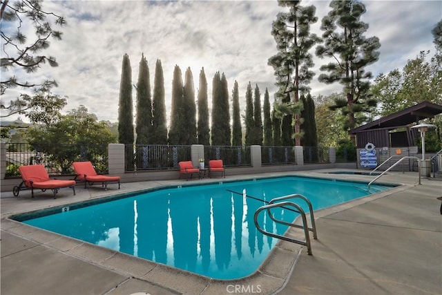 pool featuring fence and a patio