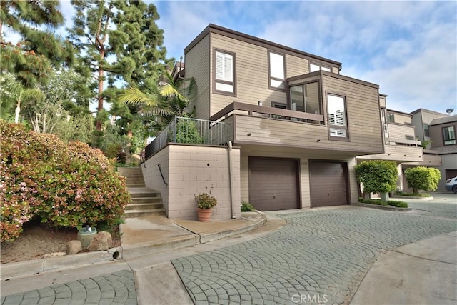 modern home with driveway, stairs, a balcony, and a garage