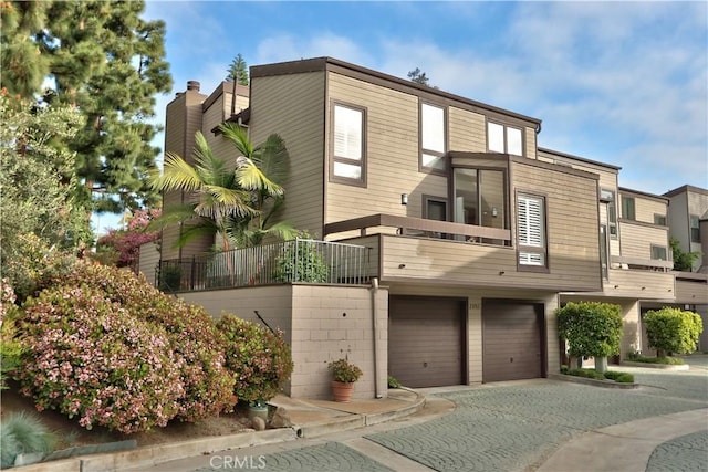 view of front facade featuring a balcony, driveway, and an attached garage