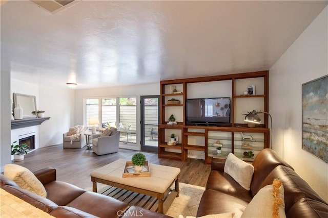 living room with a fireplace, wood finished floors, and visible vents