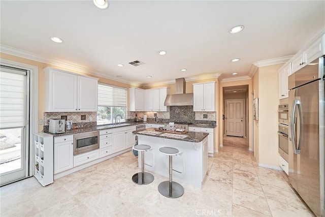 1961 W Snead St, La Habra, CA 90631 - kitchen with stainless steel appliances, wall chimney range hood, a kitchen island, a kitchen breakfast bar, and backsplash