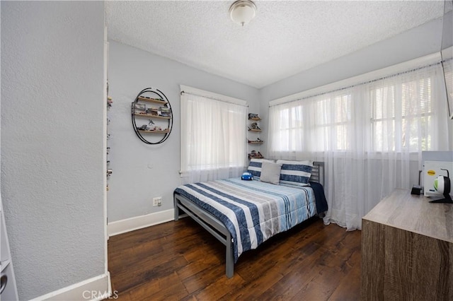 bedroom with dark wood finished floors, baseboards, and a textured ceiling