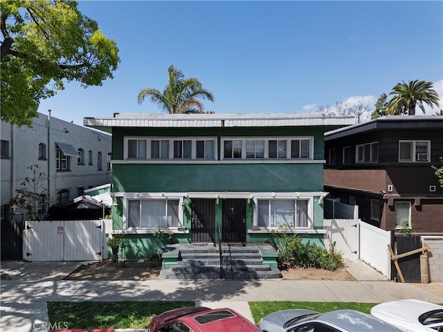 view of property with fence, uncovered parking, a gate, and stucco siding