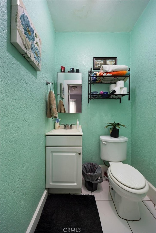 half bathroom featuring vanity, tile patterned flooring, and toilet