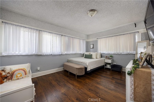 bedroom featuring dark wood finished floors, baseboards, and a textured ceiling