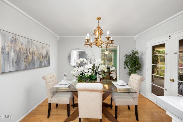 dining space with light wood-type flooring, ornamental molding, and a notable chandelier