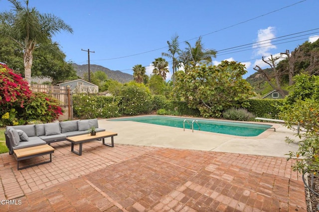 view of pool with an outdoor living space, a patio area, fence, a mountain view, and a fenced in pool