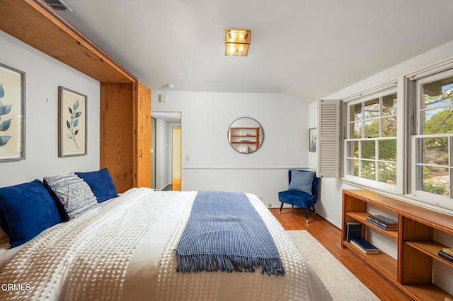 bedroom with lofted ceiling, wood finished floors, and visible vents