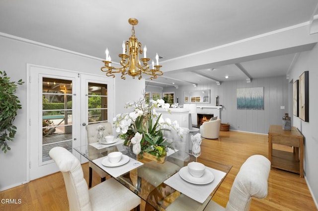 dining area with an inviting chandelier, french doors, light wood finished floors, a fireplace, and beam ceiling