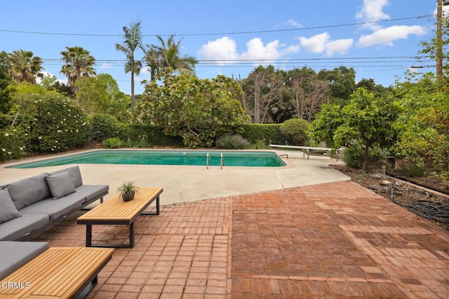 view of pool with outdoor lounge area, a fenced in pool, a patio, and a diving board