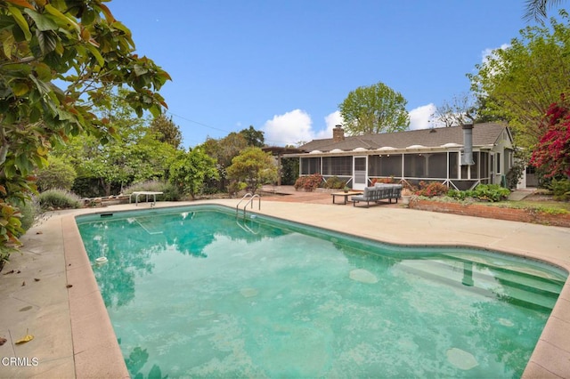 outdoor pool featuring a sunroom, a patio, and a diving board