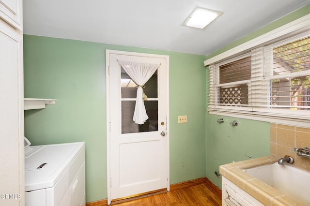 clothes washing area featuring light wood-style flooring, a sink, baseboards, independent washer and dryer, and laundry area