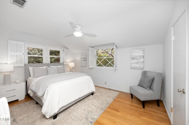 bedroom with vaulted ceiling, wood finished floors, visible vents, and baseboards