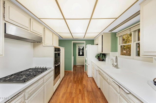 kitchen with stainless steel gas cooktop, under cabinet range hood, light countertops, and light wood-style flooring