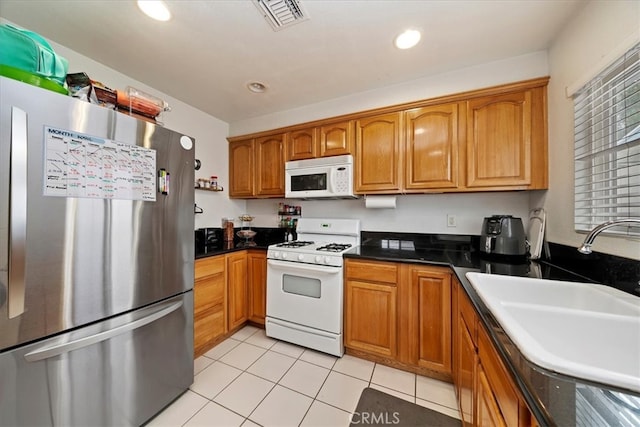 4423 N Sunflower Ave, Covina, CA 91724 - kitchen with brown cabinets, visible vents, light tile patterned floors, a sink, and white appliances