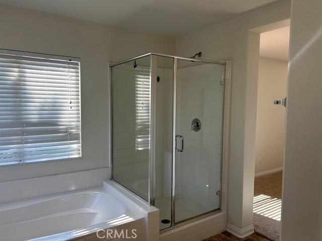 bathroom featuring a shower stall and a bath