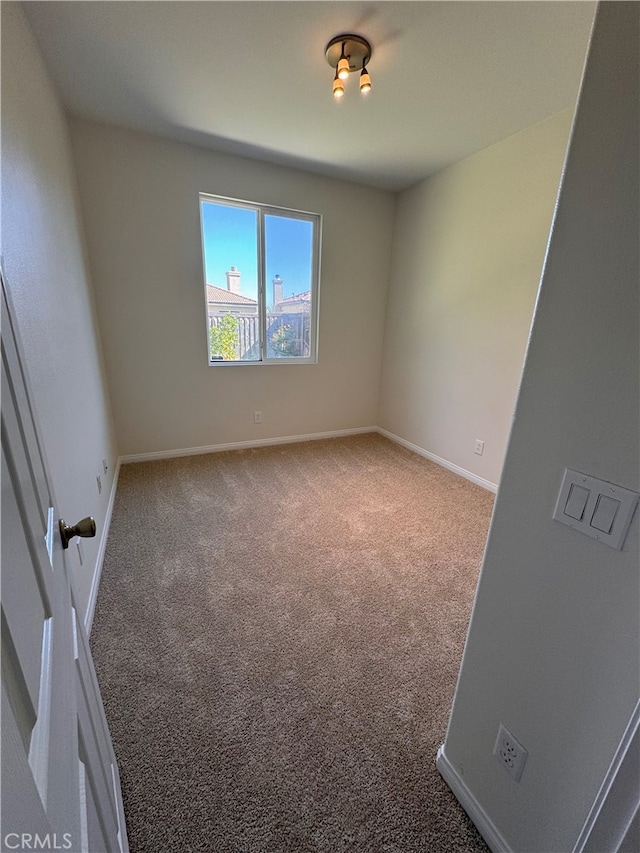 carpeted empty room featuring baseboards