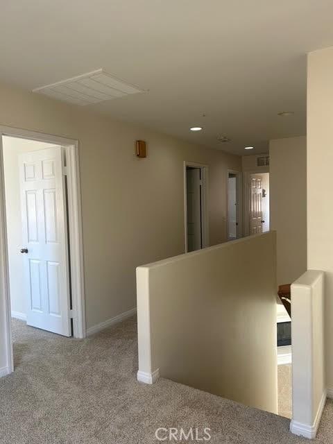 corridor with baseboards, an upstairs landing, and carpet