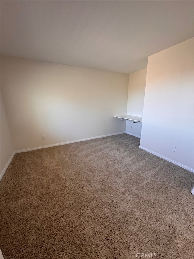 carpeted spare room featuring baseboards