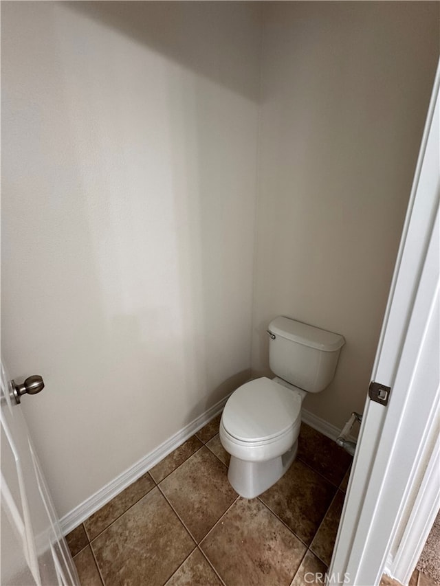 bathroom featuring toilet, baseboards, and tile patterned floors
