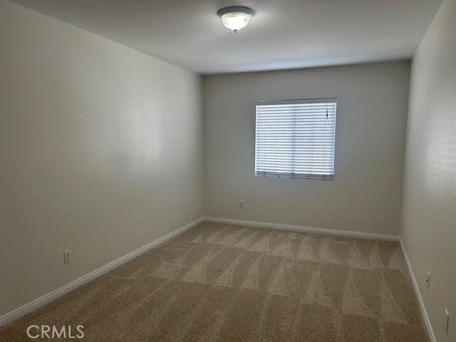 carpeted spare room with baseboards