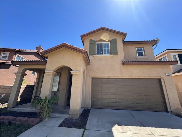 mediterranean / spanish-style house with a tiled roof, stucco siding, driveway, and a garage