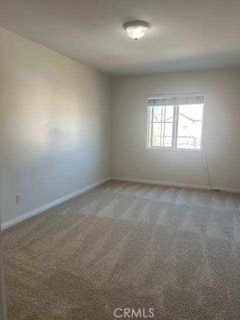carpeted spare room featuring baseboards