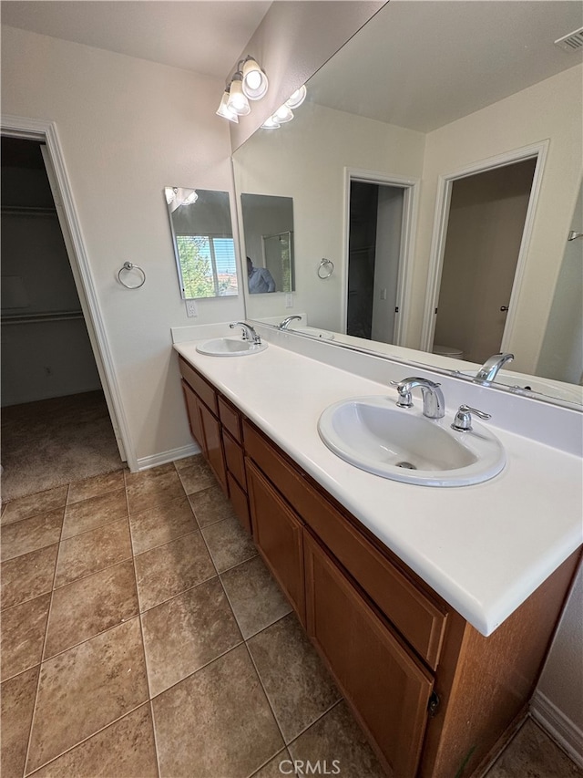 full bath with a sink, double vanity, a spacious closet, and visible vents