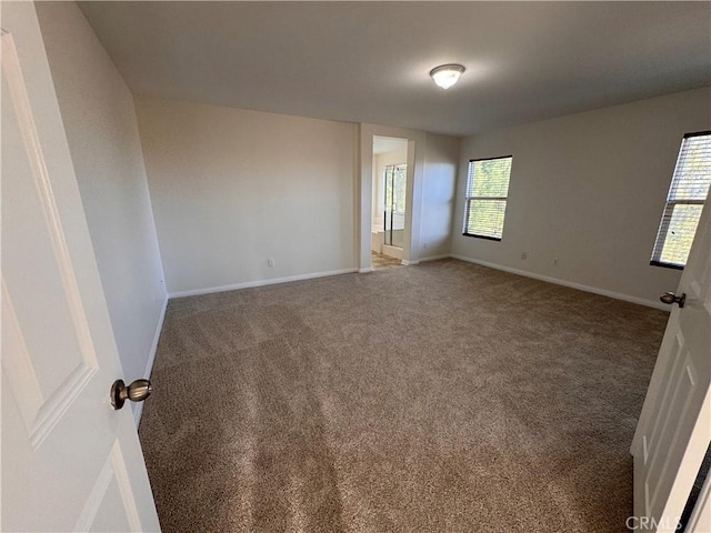 empty room featuring carpet and baseboards