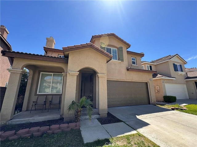 mediterranean / spanish home featuring a porch, stucco siding, and an attached garage