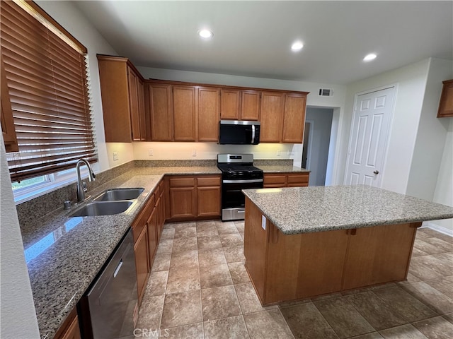 kitchen with brown cabinetry, stainless steel appliances, visible vents, and a sink