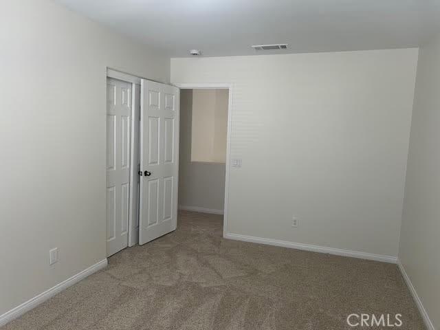 carpeted spare room featuring baseboards and visible vents