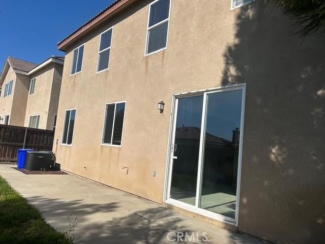 rear view of house with fence, a patio, and stucco siding