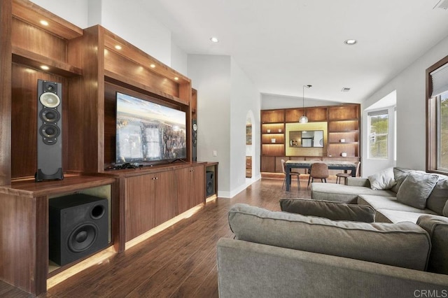 12502 Arboleda Vista Dr, Valley Center, CA 92082 - living room with built in shelves, dark wood-type flooring, arched walkways, lofted ceiling, and baseboards