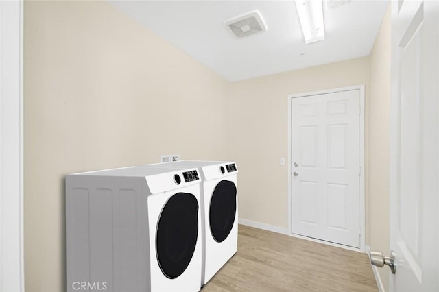 washroom with light wood-style floors, washing machine and clothes dryer, baseboards, and laundry area