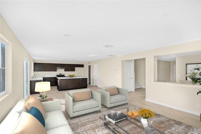 living room with stairway, visible vents, light wood finished floors, and baseboards