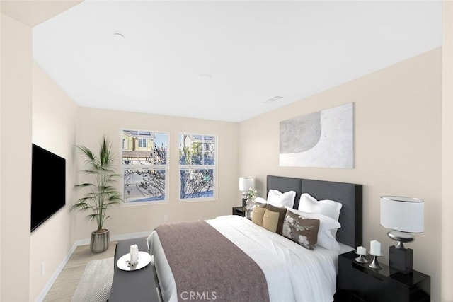 bedroom with baseboards, wood finished floors, and visible vents