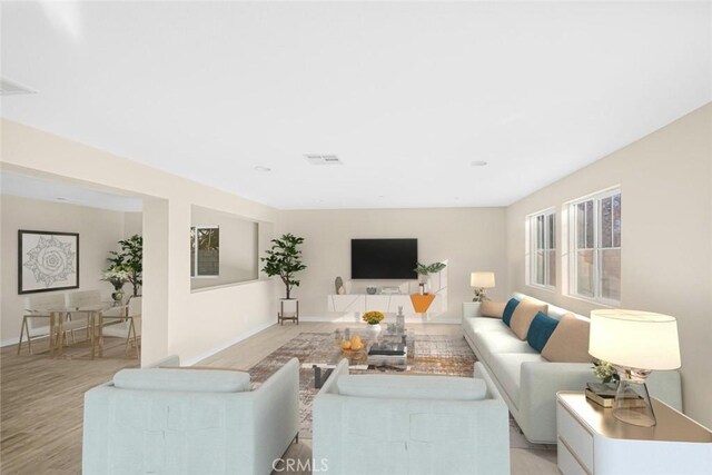 living area featuring light wood-type flooring, baseboards, and visible vents