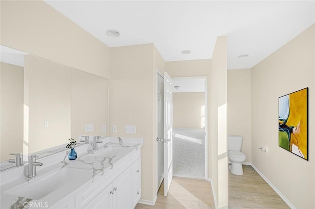 full bath with wood finished floors, a sink, double vanity, and toilet