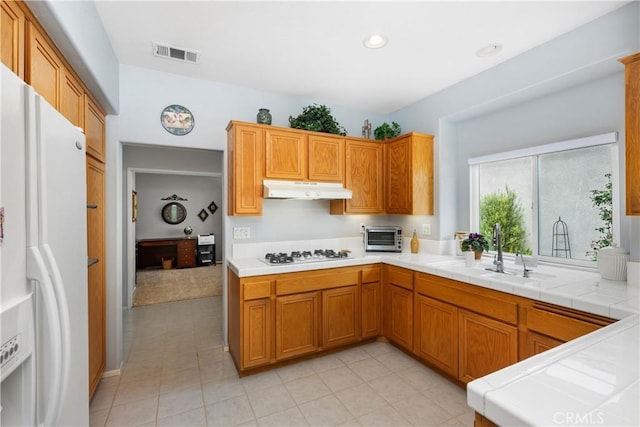 40310 Via Tonada, Murrieta, CA 92562 - kitchen with tile counters, under cabinet range hood, visible vents, a sink, and white appliances