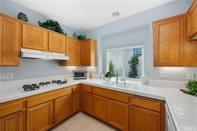 40310 Via Tonada, Murrieta, CA 92562 - kitchen with brown cabinets, a toaster, under cabinet range hood, a sink, and white gas cooktop