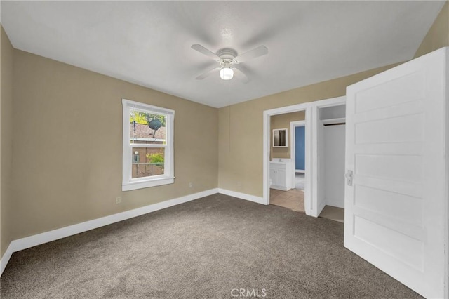 unfurnished bedroom featuring dark carpet, a ceiling fan, and baseboards