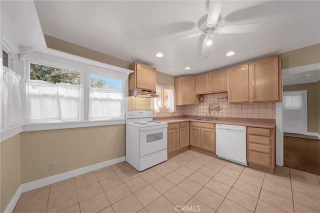 kitchen featuring white appliances, decorative backsplash, under cabinet range hood, light countertops, and a sink