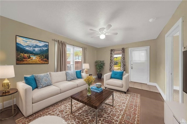 living area featuring ceiling fan, plenty of natural light, and baseboards