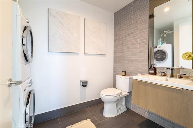 bathroom featuring tile patterned floors, toilet, stacked washer / drying machine, and vanity